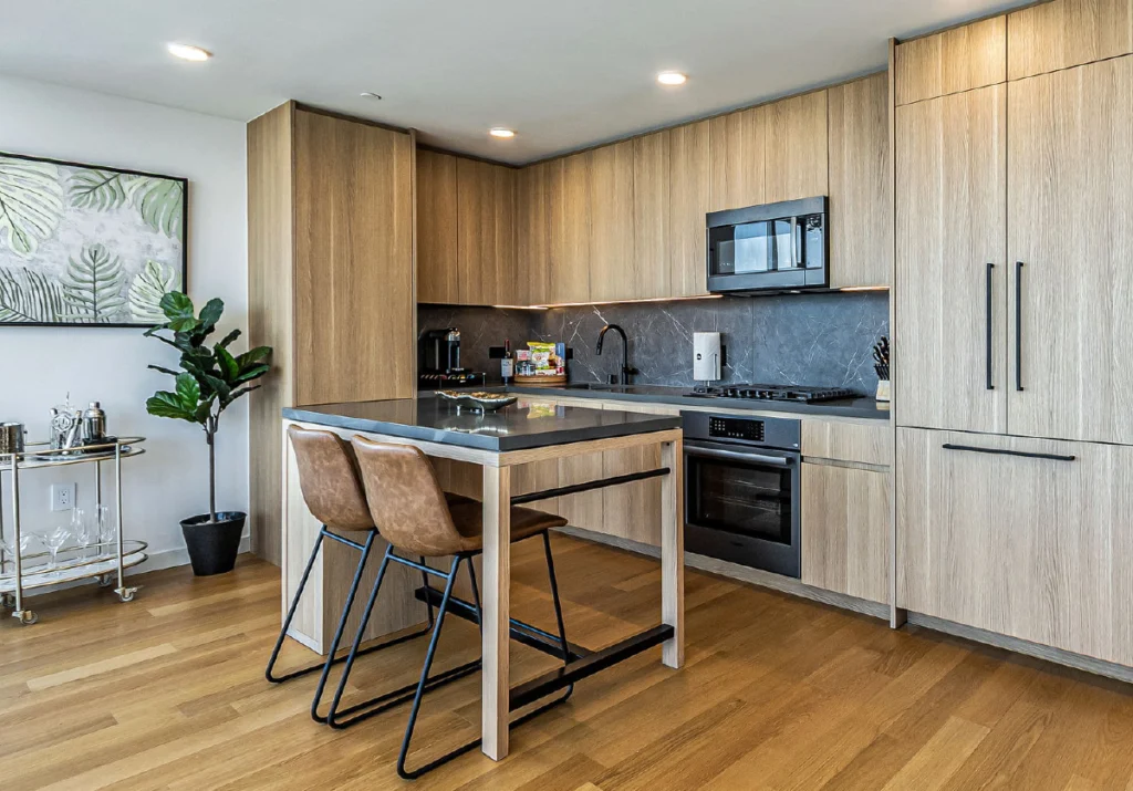 A modern kitchen with light wood cabinets and dark finishes